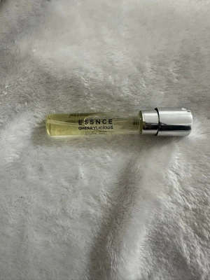 Essence Cherrylicious Eau de Parfum - Parfym från Essence i doften Cherrylicious. Kommer i en smal, genomskinlig glasflaska med silverfärgat lock. Perfekt att ha med i väskan för en fräsch doft av körsbär när du är på språng.
