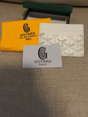 Vit kortfodral från Goy4ard - Snyggt vitt kortfodral från Goy4ard med det klassiska mönstret och loggan tryckt framtill. Tillverkad i exklusivt läder och har flera fack för kort. Kommer med originalask och tygpåse. Perfekt för dig som vill ha något stilrent och lyxigt i fickan.
