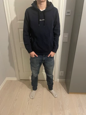 Hollister hoodie mörkblå - Tja säljer en Snygg mörkblå hoodie från Hollister med klassisk logga på bröstet. Hoodien har huva med dragsko och en stor magficka framtill. Perfekt för en avslappnad och stilren look. Tillverkad i mjukt och bekvämt material. Storlek M passar bra på killen på bilden som är ungefär 183cm lång😁skick 10/10 inga defekter🙌🏼någon mer fråga eller fundering hör av dig🤩mvh premium fashion🤗