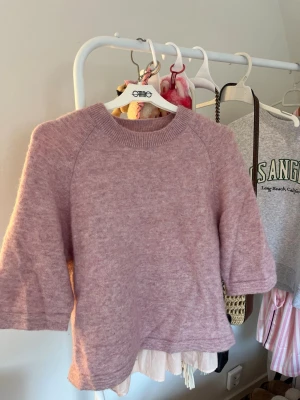 Ljusrosa stickad tröja från & Other Stories - Mysig stickad tröja i ljuslila från & Other Stories. Tröjan har rund halsringning, trekvartsärmar och är gjord i en mjuk, fluffig ullblandning. Perfekt för lager-på-lager och en chill look.