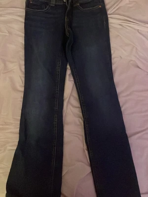 Mörkblå bootcut jeans - Snygga mörkblå bootcut jeans med klassiska fickor bak och fram. Jeansen har kontrastsömmar och är tillverkade i denim med lätt stretch. Perfekta för dig som gillar en tidlös och avslappnad stil.