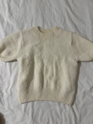 Krämvit stickad tröja Gina Tricot - Mysig krämvit stickad tröja med trekvartsärmar från Gina Tricot med rund halsringning och ribbade muddar vid ärmslut och nederkant. Tröjan har en enkel, klassisk design och är tillverkad i ett mjukt material som passar perfekt för kyligare dagar. Den har en liten fläck vid kragen som endast syns när tröjan inte bärs (kolla bilden)🥰❤️