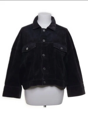 Mörkblå overshirt i manchester - Stilren mörkblå overshirt i manchestertyg med bred krage och knäppning framtill. Två bröstfickor med knappdetaljer och avslappnad, boxig passform. Perfekt för lager på lager och ger en cool vibe till din outfit.