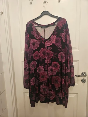 Festlig lilamönstrad tunika - Underbar festlig lilamönstrad tunika från Yours i viskoskvalitet. Transperent lång ärm med resår nedtill. Generös i storlek. I använt gott skick. Nypris 399 kr