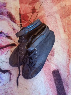 Svarta kilklackade stövletter med snörning från h&m - Snygga svarta stövletter med kilklack, snörning framtill och kardborreband vid ankeln. Skorna är i mockaliknande material och har en sportig men ändå stilren look. Perfekta för dig som vill ha både höjd och komfort.