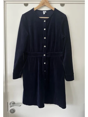 & Other Stories mörkblå sammetsklänning, 40 / L - Stilren mörkblå / marinblå / navy klänning i sammet från & Other Stories i storlek 40. Klassisk modell med långa ärmar och rund halsringning, i mjukaste lena sammetstyget. Vacker knäppning framtill med silverfärgade knappar och ett insytt band i midjan, för smickrande siluett. Men bäst av allt: it has pockets!! 🥳 Mycket gott skick, som ny. Nypris 1490:-    Skickas mot porto, kan även hämtas i Stockholm.  