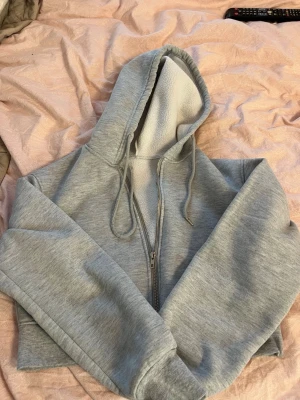 Grå zip hoodie med huva - Snygg grå hoodie med dragkedja och huva. Mjuk insida och ribbade muddar vid ärmslut och nederkant. Perfekt för en avslappnad stil och enkel att matcha med andra plagg. Storleken på denna passa en xs 