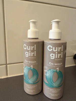 Curl Girl Nordic Co-wash balsam helt nya - Två flaskor Curl Girl Nordic Co-wash cleansing conditioner, 200 ml vardera. Vegansk formula med kokosolja, mangoolja och linfröolja. Perfekt för lockigt hår, rengör, återfuktar och motverkar friss. Snygg beige flaska med pump och turkost motiv. 