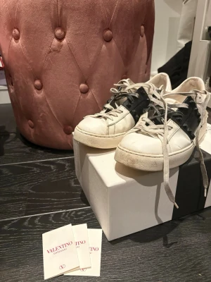 Valentino Garavani vita sneakers - Säljer ett par vita sneakers från Valentino Garavani med svarta detaljer och nitar på sidan. Skorna har en chunky sula. Dom är ju uppenbarligen använda, därav det billiga priset. (Dom är äkta) 
