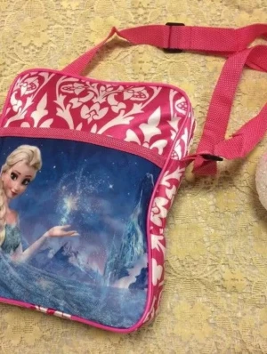 Rosa Frozen ryggsäck med Elsa-motiv - Cool ryggsäck med motiv från Frozen och Elsa på framsidan. Väskan är rosa med vita mönster och har justerbara axelband. Materialet är syntet och designen är färgglad och fantasifull, perfekt för dig som gillar Disney och magiska äventyr.