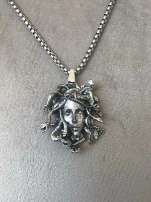 Silverfärgat halsband med Medusa-inspirerat hänge - Unikt och detaljrikt halsband med Medusa-inspirerat hänge i silverfärg. Trendig statement-accessoar som passar både vardag och fest. Fint skick och snygg kedja med bra längd. ✨