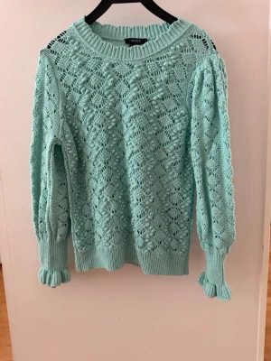 Mintgrön stickad tröja från Lindex - Supersöt mintgrön stickad tröja från Lindex med hålmönster och puffärmar. Tröjan är ribbad. Materialet är mjukt och lätt, perfekt för en lite kallare sommarkväll.