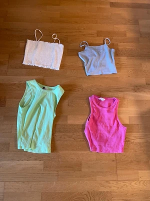 Färgglada croppade linnen - Fyra croppade linnen i olika färger: vitt bandeau med smala axelband, ljusblått med tunna axelband, limegrönt och rosa ärmlöst linne. Perfekta för varma dagar och att styla lager på lager.
