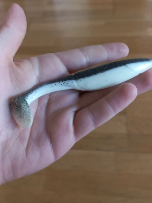 Mjukplastfisk för fiske, svartvit - En jigg i svart och vitt med paddelstjärt, perfekt som bete vid fiske. Fisken har en realistisk form och är täckt av små svarta/gråa prickar på ovansidan. Tillverkad i mjuk plast för naturlig rörelse i vattnet.