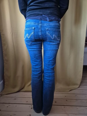 Low waist bootcut jeans från Nelly  - Jättefina low waist bootcut jeans från Nelly i storlek 38(M). Med vit sömm och broderade detaljer på fickorna. Har bara använts ett fåtal gånger och är i nyskick. De är helt intakta och som nyköpta. Säljer pga att de längre inte är min stil. Jag är 173 cm lång och har långa ben. Hör av dig om du har några frågor eller behöver mer information💕