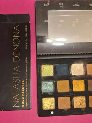 Natasha Denona Gold Palette ögonskugga - Natasha Denona Gold Palette med 15 ögonskuggor i nyanser av guld, grönt, blått, brunt och beige. Paletten innehåller både matta och skimrande färger, perfekt för kreativa och glamorösa looks. Kommer i en snygg svart förpackning med spegel. Några skuggor är swatchade, testade. En fin palett.