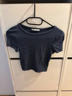 Mörkblå t-shirt från Zara - En enkel och stilren mörkblå t-shirt från Zara med rund halsringning och korta ärmar. Perfekt basplagg som passar till det mesta och är lätt att matcha. Tillverkad i mjuk bomull för en bekväm känsla.