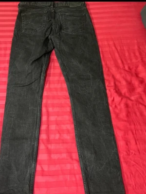 Svarta slim fit jeans - Snygga svarta slim fit jeans med lätt tvättad look och klassiska bakfickor. Jeansen har bälteshällor och raka ben, perfekta för en trendig och avslappnad stil. Materialet är troligtvis bomullsdenim med stretch för extra komfort.