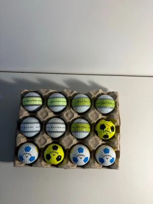 Truvis/ stripes  - Säljer ett set med 12 golfbollar från TaylorMade och Callaway. Bollarna är vita, gula och har olika mönster, bland annat blå och svarta detaljer. Perfekt för dig som vill fylla på golfutrustningen med bollar från kända märken.