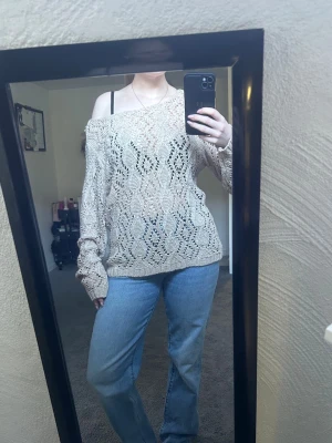 Beige stickad tröja med hålmönster - Säljer en beige stickad tröja med snyggt hålmönster och avslappnad passform. Tröjan har långa ärmar och bred ribb vid nederkant och ärmslut. Den är gjord i ett lätt material och har en off shoulder-design som ger en cool look. Storlek L men skulle säga att den är mer åt M.