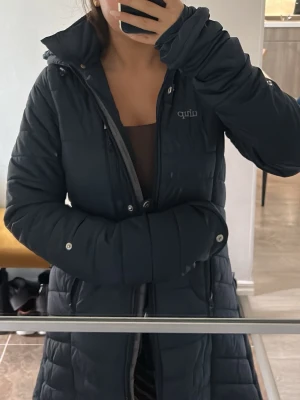 Marinblå jacka från Uhip - Snygg marinblå ridjacka från Uhip med längre passform och vadderad design. Jackan har huva, dragkedja och tryckknappar framtill samt två fickor med dragkedja. Man får super fin form i kroppen