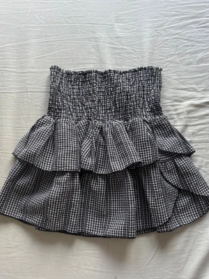 Rutig volangkjol  - Supersöt kort kjol från Neo Noir i svartvitt rutigt mönster. Kjolen har smock i midjan och dubbla volanger 
