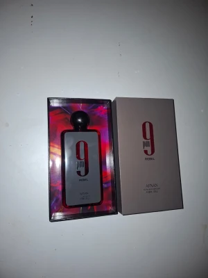 Afnan 9PM Rebel parfym 100ml - Afnan 9PM Rebel är en parfym i en snygg, mörkröd glasflaska med svart, rund kork. Flaskan har en modern design med tydlig logga och levereras i en stilren ask. Perfekt för dig som gillar unika och djärva dofter. Den är helt ny aldrig använd, bara att fråga om ni vill ha fler bilder