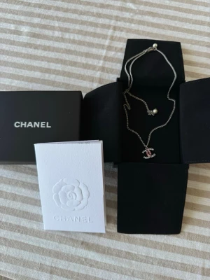 Chanel - CC logga halsband  - Halsband från Chanel med silverfärgad kedja och ikonisk CC-logga som hänge. Sparsamt använd och är i väldigt fint skick. Kommer i originalask och med certifikat samt kvitto. 