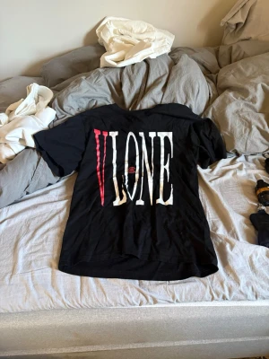 Svart VLONE t-shirt med draktryck - Säljer en svart t-shirt från VLONE med stort vitt och rött tryck på framsidan och en stor röd drake på baksidan. T-shirten har korta ärmar och en normal passform. Perfekt för dig som gillar streetwear och vill sticka ut.