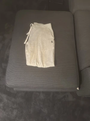 Grå mjukisbyxor från Polo Ralph Lauren - Snygga och bekväma grå mjukisbyxor från Polo Ralph Lauren med dragsko i midjan och klassisk broderad logga på benet. Perfekta för en avslappnad stil och sköna att ha på sig hela dagen.