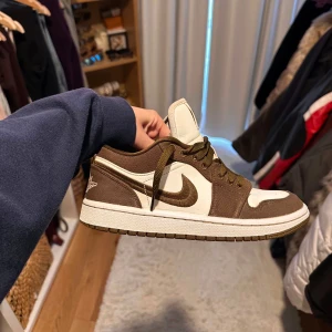 Brown  Air Jordan 1 Low - Säljer ett par Air Jordan 1 Low i brunt och vitt med klassisk swoosh på sidan. Skorna har bruna snören, perforerad tåbox och en låg siluett. Perfekta för dig som gillar streetwear och vill ha en ikonisk sneaker i garderoben. Skorna är i perfekt skick förutom den lilla creasen framme som även syns på bild🕺🏻Ses bara i Göteborg💥storlek 38 men tycker dem är mindre än så i storlek, därför jag säljer. Ni kan även se dem stylade på mig på sista bilden. 