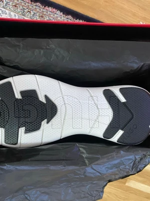 HUGO vita och svarta sneakers - Snygga sneakers från HUGO med vit sula och svarta detaljer undertill. Skorna har en modern design och tydlig logga på sulan. Perfekta för dig som vill ha en stilren och trendig look. Kommer i originalkartong.