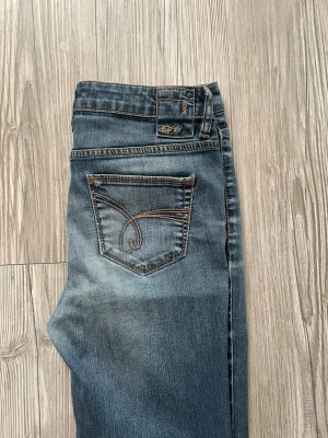 Blå bootcut jeans från Esprit - Säljer ett par blå baggy jeans från Esprit med snygg broderad bakficka. De är lite slitna längst ner där bak på jeansen men annars i nyskick. 