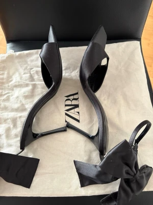 Svarta klackar med rosett från Zara - Har använt bara 1 gång. Klackhöjd:9 cm, nypris: 500kr