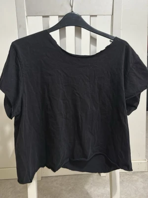 Svart croppad t-shirt - En enkel svart croppad t-shirt med rund hals och korta ärmar. Perfekt basplagg till garderoben och lätt att matcha med olika stilar. 