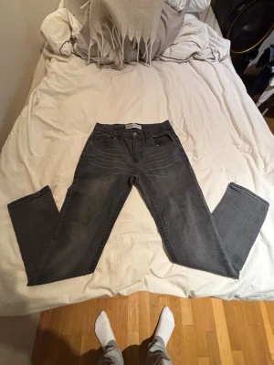  jeans Levi's - Säljer ett par grå jeans från Levi's med klassisk femficksdesign och raka ben. Jeansen har en diskret tvättad look och Levi's ikoniska röda etikett på bakfickan. Perfekta för en avslappnad och stilren outfit.