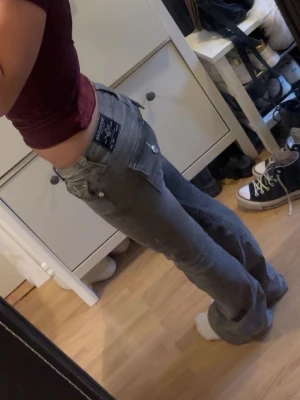 Gråa bootcut jeans från True Religion - Säljer ett par gråa bootcut jeans från True religion med låg midja och klassiska femficksdetaljer. Jeansen har en snygg passform som framhäver siluetten och är tillverkade i denim med lite stretch för extra komfort. Perfekta för dig som gillar en avslappnad och trendig look. W24 passar även W25. Några jätte snygga anmärkningar men syns knappast (kolla sista två bilderna)