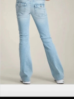 Ljusblå bootcut jeans med slitningar - Säljer ett par ljusblå bootcut jeans med slitningar på knäna från Gina. Storlek 158!