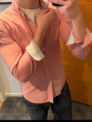 Rosa skjorta från Ralph Lauren - Säljer en klassisk rosa skjorta från Ralph Lauren med button-down krage och broderad logga på bröstet. Skjortan har vita knappar och lång ärm med kontrastfärgad insida på manschetten. Perfekt till jeans eller chinos!