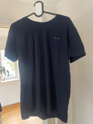 Mörkblå t-shirt från GANT - Snygg mörkblå t-shirt från GANT med logga på bröstet. Klassisk rund halsringning och korta ärmar. Tillverkad i mjuk bomull och perfekt basplagg 
