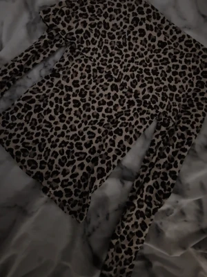 Leopardmönstrad offshoulder topp - Säljer en snygg offshoulder topp med leopardmönster och långa ärmar. Toppen har en volangdetalj över axlarna och är i en beige och brun färgton. Perfekt för dig som vill sticka ut och gillar trendiga prints.