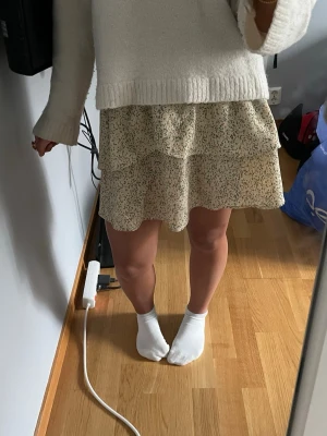 Blommig volangkjol i beigegul - Supersöt kortkjol i beige-gul färg med småblommigt mönster i grönt och rosa från LMTD. Kjolen har bred resår i midjan och dubbla volanger som ger en flowy känsla. Perfekt för vår och sommar, lätt att matcha med en enkel topp. Lägg gärna prisförslag!