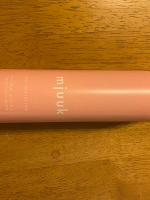 Mjuuk Heat Protection spray - Säljer en rosa värmeskyddsspray från Mjuuk. Flaskan rymmer 250 ml och är 100% vegansk. Perfekt för att skydda håret vid styling och ger naturlig glans. Snygg och stilren design med vit text på flaskan.