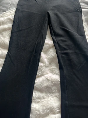 Svarta bootcut leggings - Säljer ett par svarta leggings med bootcut-ben. De är tillverkade i ett mjukt och stretchigt material som sitter skönt och följer kroppen. Perfekta för dig som vill ha en enkel och stilren look med lite extra vidd nedtill.