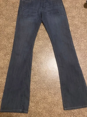 Vintage  bootcut jeans från Miss Natalie - Snygga blå bootcut jeans från Miss Natalie med dekorativa nitar och kontrastsömmar på bakfickorna. Klassisk femficksmodell i mjukt denimtyg, perfekta för en avslappnad och trendig look.