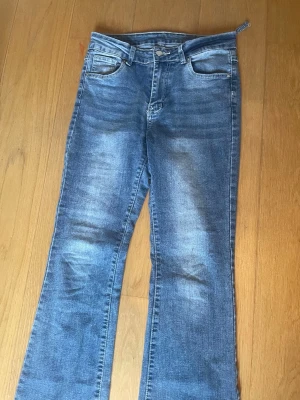 Blå bootcut jeans - Säljer ett par klassiska blå bootcut jeans. Jeansen har fem fickor, bälteshällor och stängs med knapp och dragkedja. Materialet är denim i bomull. Perfekta för en avslappnad och trendig look.