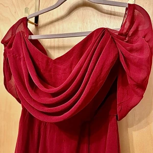 Vinröd offshoulder långklänning från Goddiva - Elegant vinröd långklänning med offshoulder-design och draperad överdel. Klänningen har en mjuk, flytande form och stängs med dragkedja i ryggen. Perfekt för speciella tillfällen där du vill sticka ut.   Längd - ca 141cm Byst - ca 37cm  Midja - ca 35cm