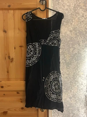 Svart kort klänning med vita mönster - Svart kortklänning med vita detaljer. Mycket bra skicka, använd fåtal gånger. Hör av vid frågor!💗