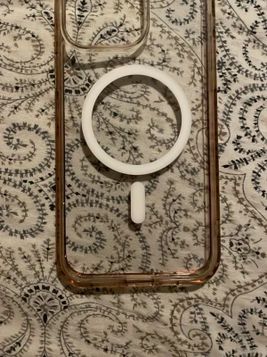 Transparent MagSafe mobilskal brun - Hej iPhone 15 MagSafe-skal (transparent)  Beskrivning: Säljer ett transparent MagSafe-skal till iPhone 15. Skalet har inbyggd magnetring så det fungerar med Apple MagSafe Charger och andra MagSafe-tillbehör.  Köpt från **Apples hemsida men används inte längre. Skalet är i bra skick och skyddar mobilen mot repor och stötar.  Passar iPhone 15 och liknande modeller.