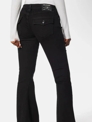 Svarta bootcut jeans True Religion - Säljer ett par svarta bootcut jeans från True Religion med fickor bak och knappdetalj. Jeansen har hög midja och klassisk logga på bakfickan. Snygg passform som framhäver siluetten och passar perfekt till en trendig streetstyle-look.säljer pågrund av för korta 